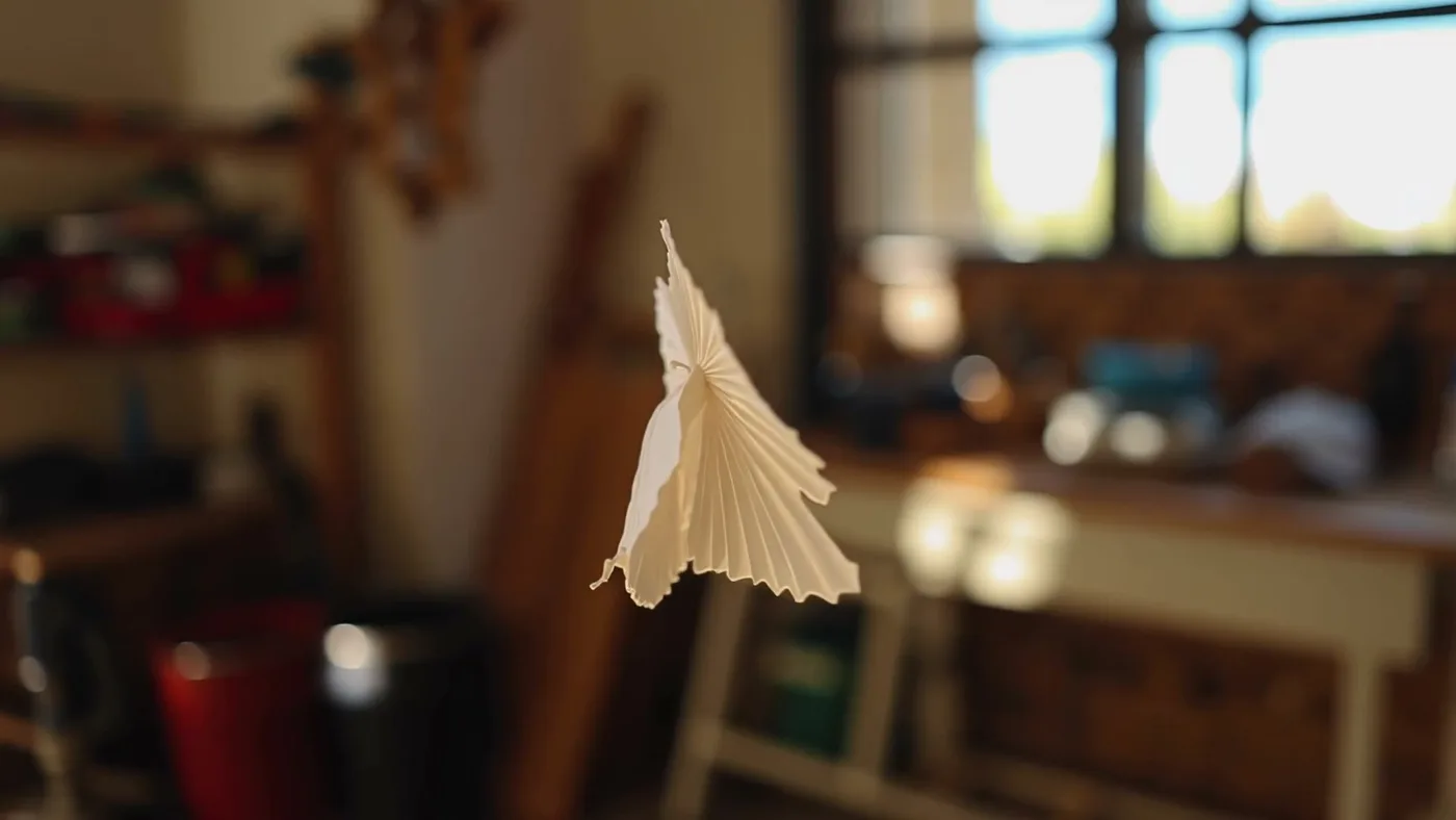 LTX 2.3 self-portrait, paper sculpture in warm workshop light